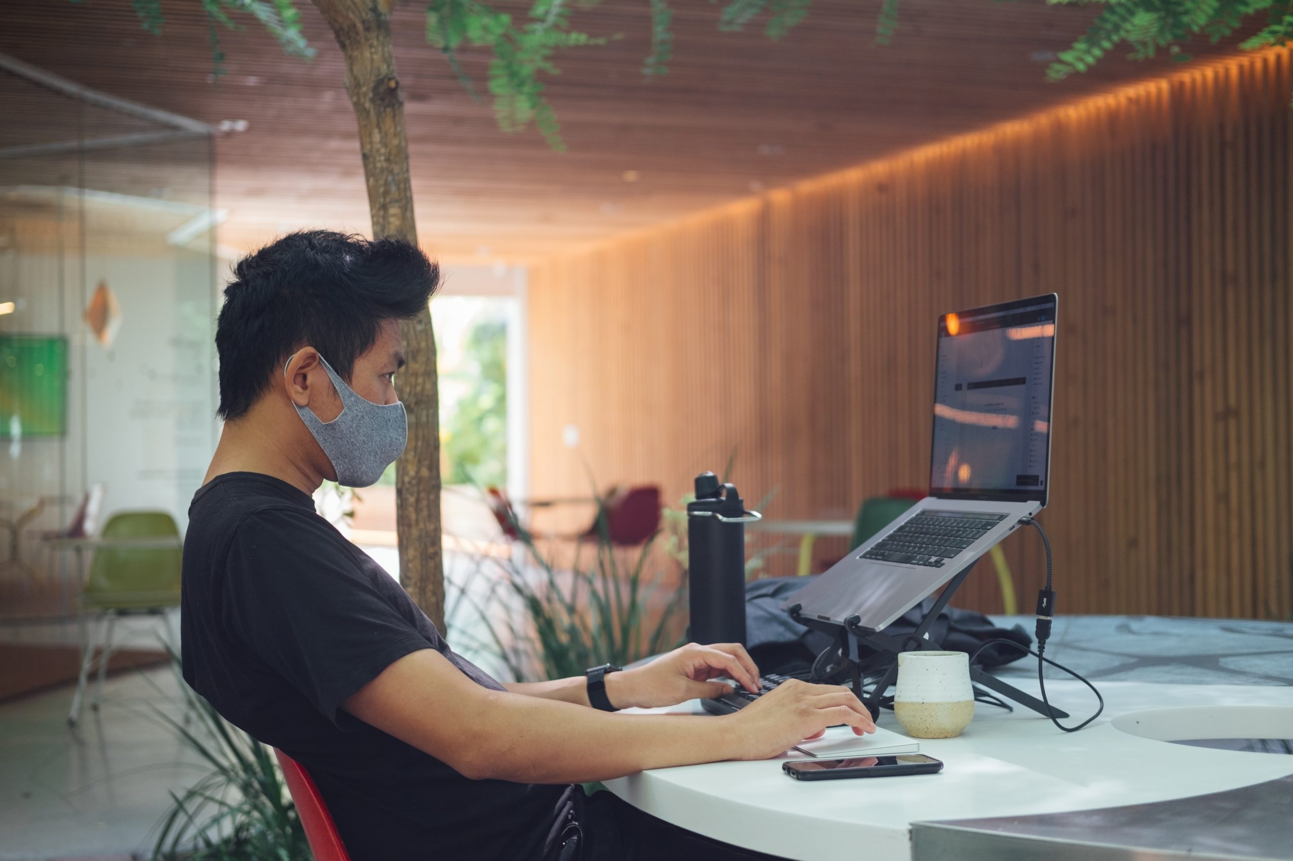 work from home, young man with protective mask on his face working remotely with his laptop