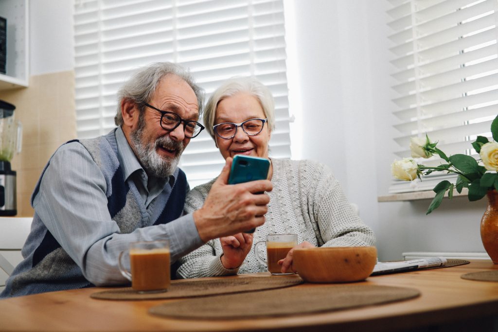 older adults using technology, adults using smartphone while drinking coffee